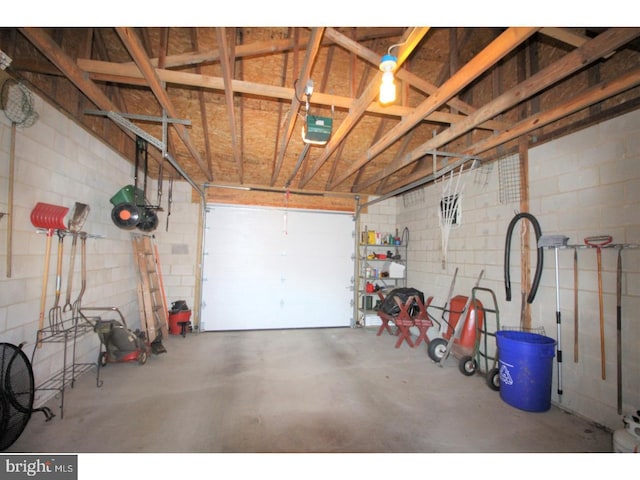 garage featuring concrete block wall and a garage door opener