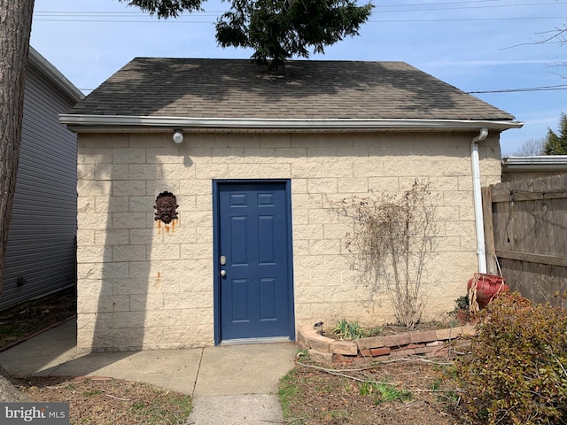 property entrance featuring a shingled roof and fence