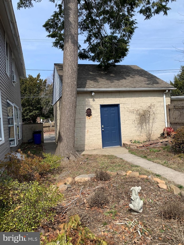 exterior space with a gate, a shingled roof, and fence