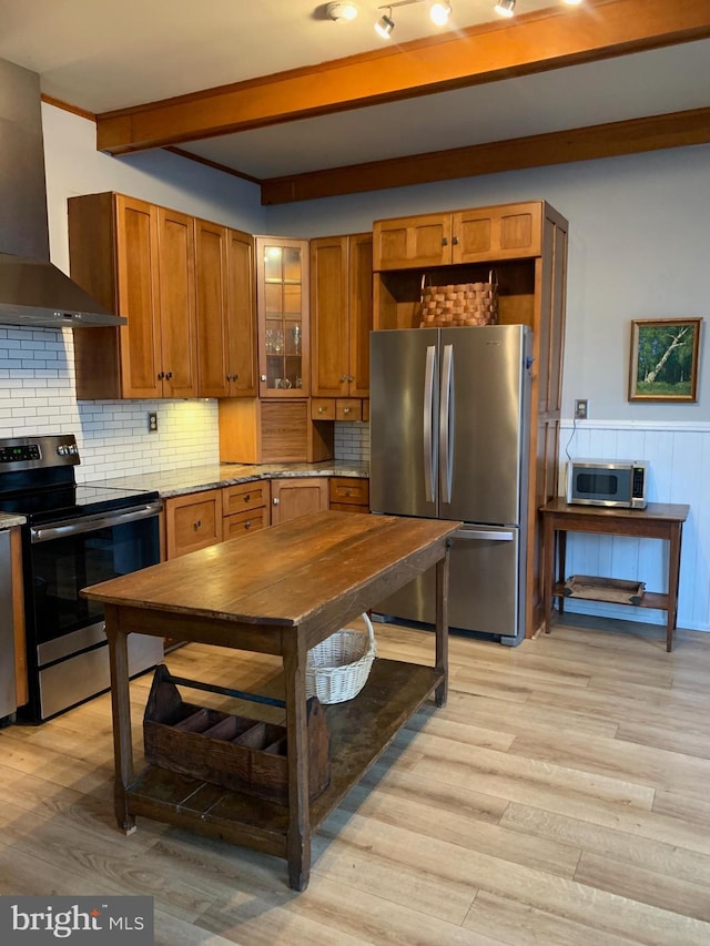 kitchen featuring stainless steel appliances, light wood-style floors, wall chimney exhaust hood, and brown cabinetry