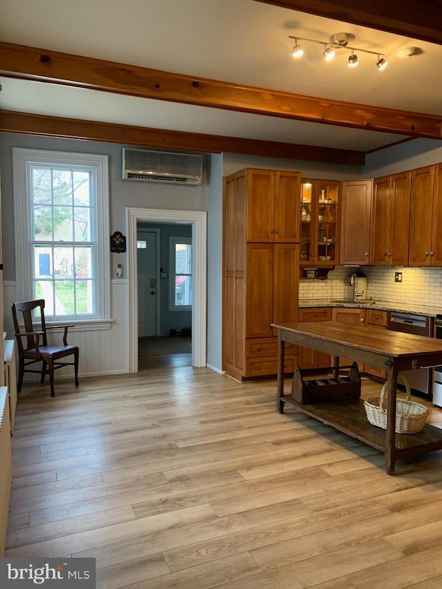 kitchen featuring beam ceiling, decorative backsplash, an AC wall unit, light wood-style floors, and brown cabinets