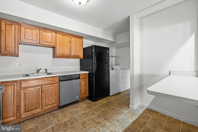 kitchen featuring a sink, stainless steel dishwasher, freestanding refrigerator, separate washer and dryer, and baseboards