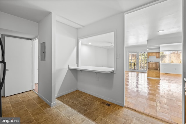 interior space with electric panel, visible vents, ceiling fan, and baseboards