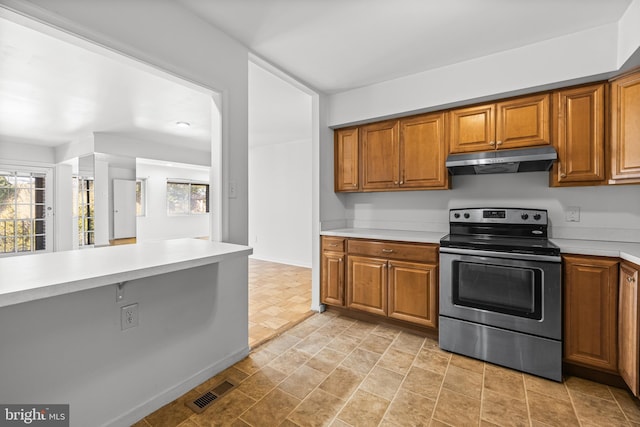 kitchen featuring visible vents, stainless steel electric range, brown cabinets, and under cabinet range hood