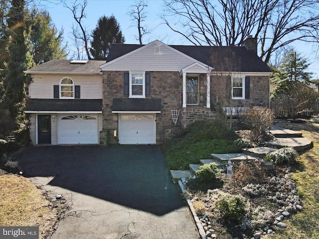 view of front of home with stone siding, an attached garage, a chimney, and driveway