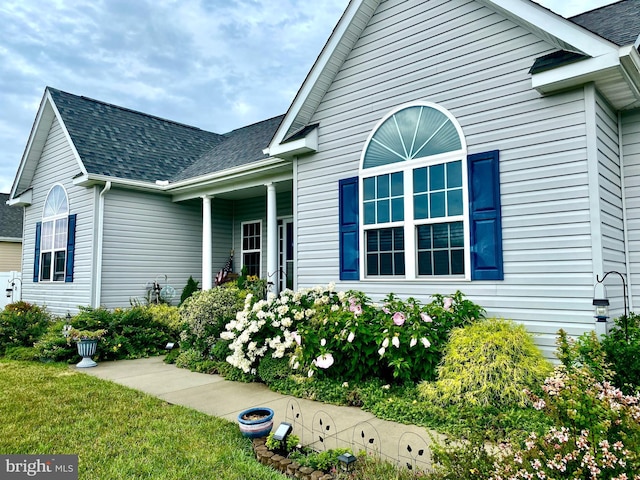 exterior space featuring roof with shingles and a front lawn