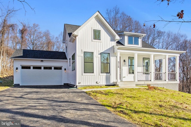 modern farmhouse style home featuring a front lawn, aphalt driveway, a porch, board and batten siding, and an attached garage