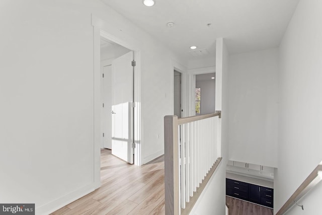 corridor with recessed lighting, baseboards, an upstairs landing, and light wood finished floors