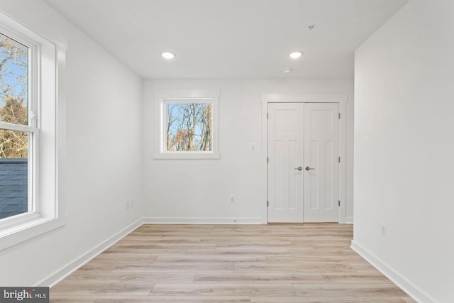 unfurnished room with a healthy amount of sunlight, baseboards, and light wood-style floors