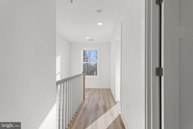 hall featuring light wood-style flooring, recessed lighting, visible vents, and baseboards