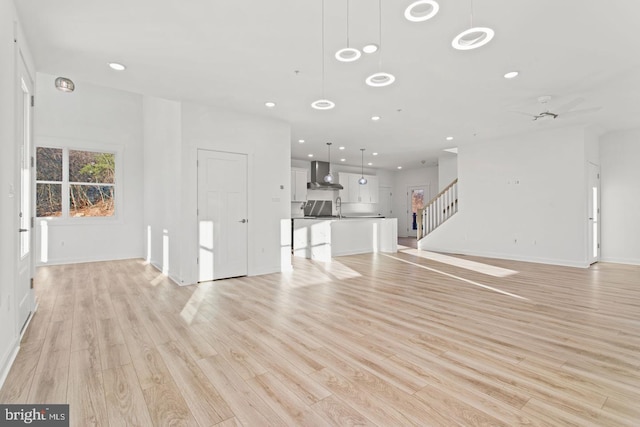 unfurnished living room featuring stairs, recessed lighting, and light wood-style floors