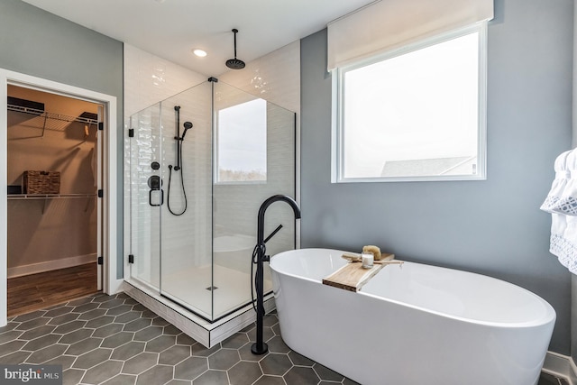 full bathroom with a healthy amount of sunlight, a stall shower, and a freestanding bath