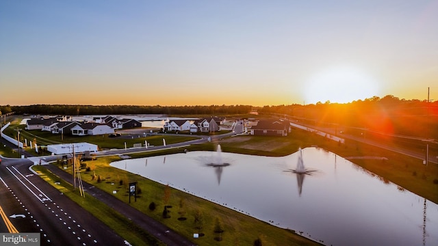 aerial view at dusk featuring a residential view and a water view