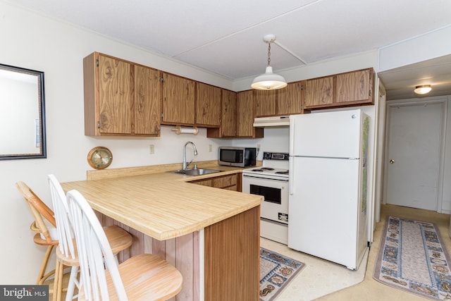 kitchen featuring a sink, under cabinet range hood, white appliances, a peninsula, and light countertops