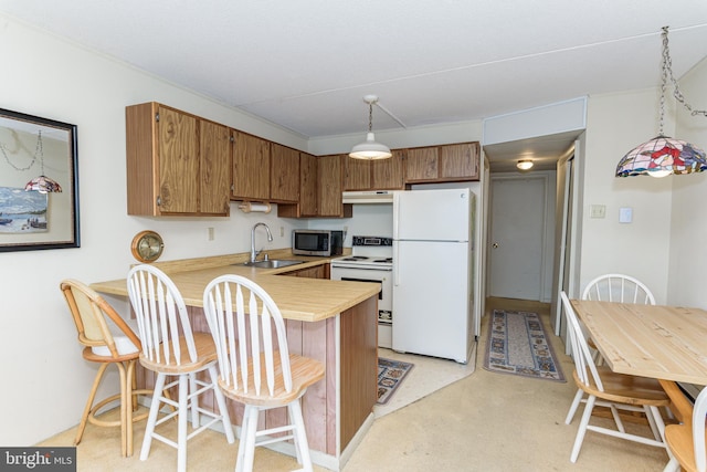 kitchen featuring white appliances, a peninsula, a sink, light countertops, and under cabinet range hood