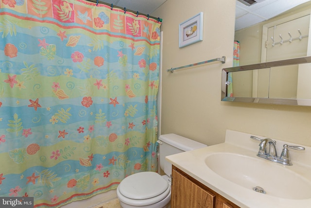 bathroom with vanity, toilet, a shower with curtain, and a paneled ceiling