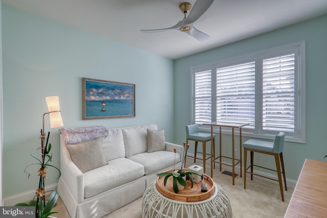 living area featuring a ceiling fan, baseboards, and carpet floors