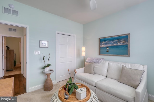 living room with carpet, visible vents, and baseboards