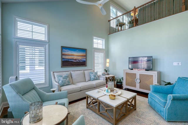 living area featuring a wealth of natural light, a high ceiling, a ceiling fan, and wood finished floors