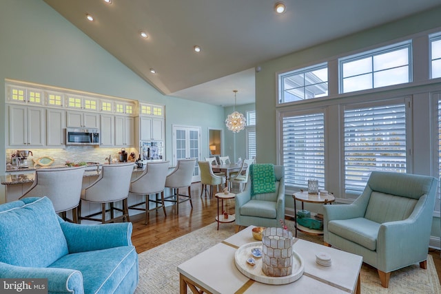 living room with recessed lighting, light wood-style flooring, and high vaulted ceiling