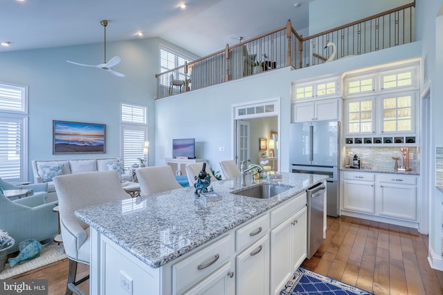 kitchen featuring a sink, open floor plan, stainless steel dishwasher, freestanding refrigerator, and dark wood-style flooring