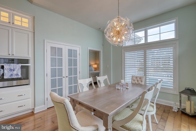 dining room featuring a notable chandelier, french doors, light wood-type flooring, and baseboards