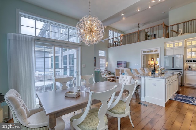 dining area with recessed lighting, light wood-style floors, a towering ceiling, and a chandelier