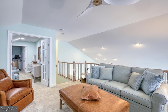 living area with baseboards, light colored carpet, and vaulted ceiling