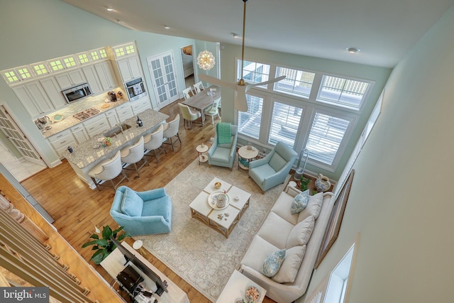 living area with light wood-type flooring and high vaulted ceiling