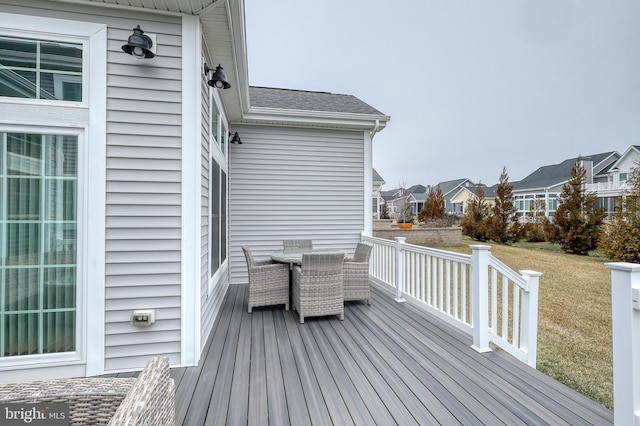 wooden terrace featuring outdoor dining area, a residential view, and a yard