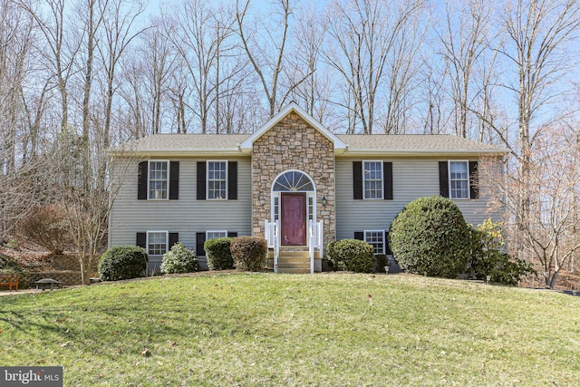 split foyer home featuring stone siding and a front yard