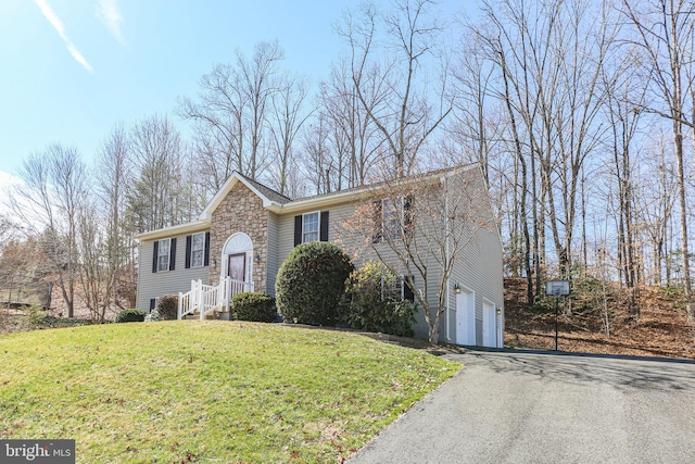 bi-level home featuring aphalt driveway, an attached garage, stone siding, and a front lawn