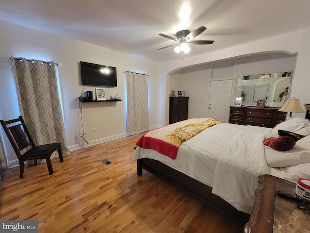 bedroom featuring ceiling fan, baseboards, arched walkways, and wood finished floors