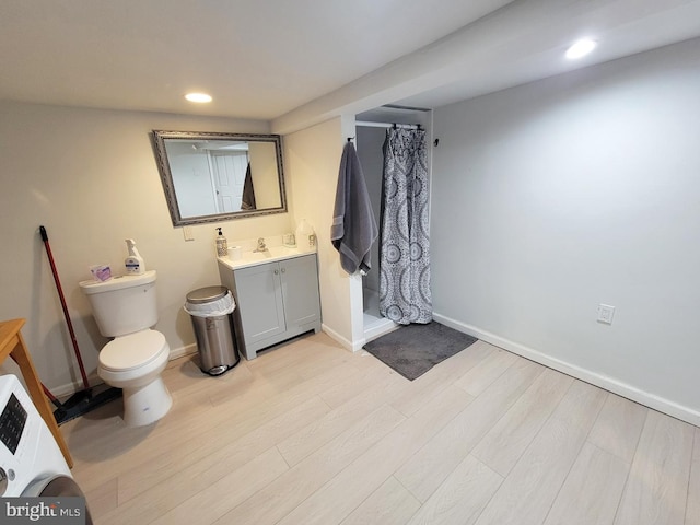 full bathroom featuring toilet, vanity, a stall shower, wood finished floors, and washer / clothes dryer