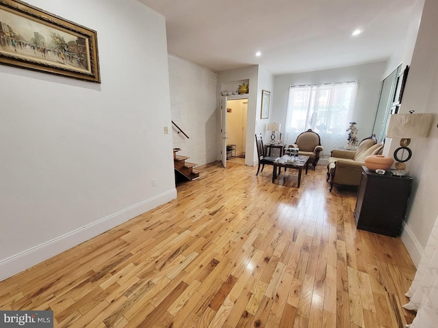 living area featuring recessed lighting, light wood-type flooring, stairs, and baseboards