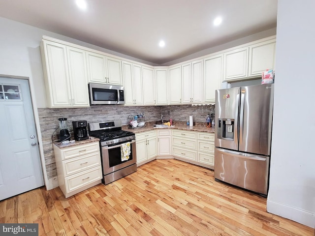 kitchen featuring light wood finished floors, tasteful backsplash, light stone counters, recessed lighting, and stainless steel appliances