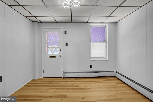 entryway with a drop ceiling, a baseboard radiator, and light wood finished floors