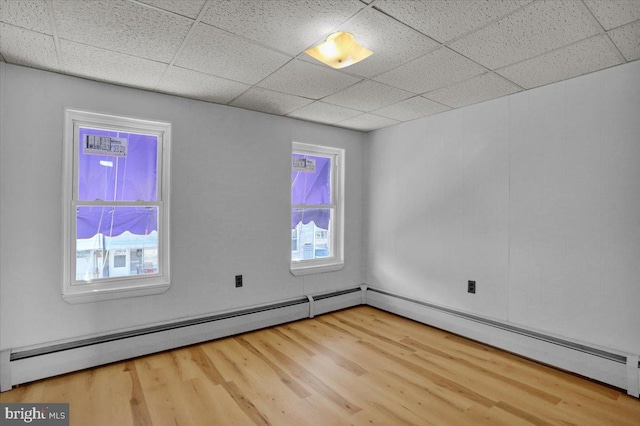 unfurnished room with a paneled ceiling, a healthy amount of sunlight, and wood finished floors