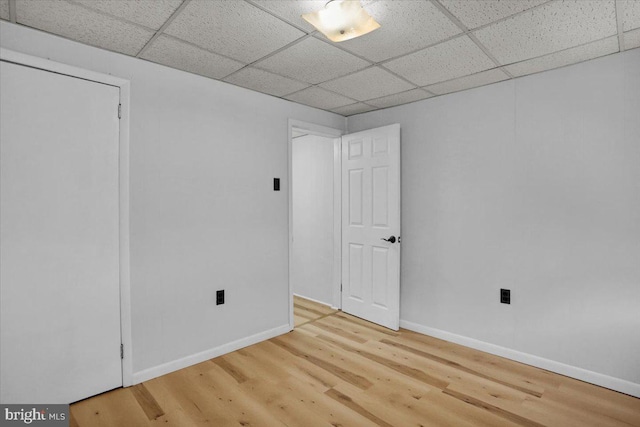 basement with wood finished floors, a paneled ceiling, and baseboards