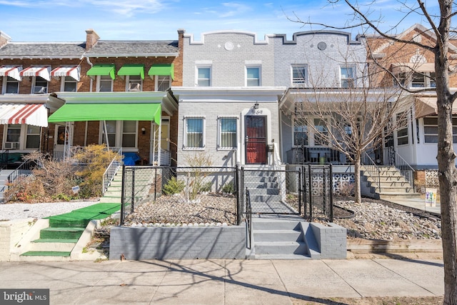 multi unit property with brick siding, a fenced front yard, and a gate