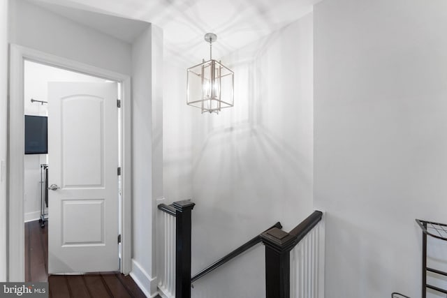 staircase with a notable chandelier and wood finished floors