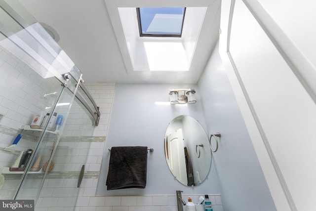 full bathroom featuring tiled shower and a skylight