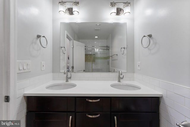 full bathroom with a shower stall, tile walls, double vanity, and a sink