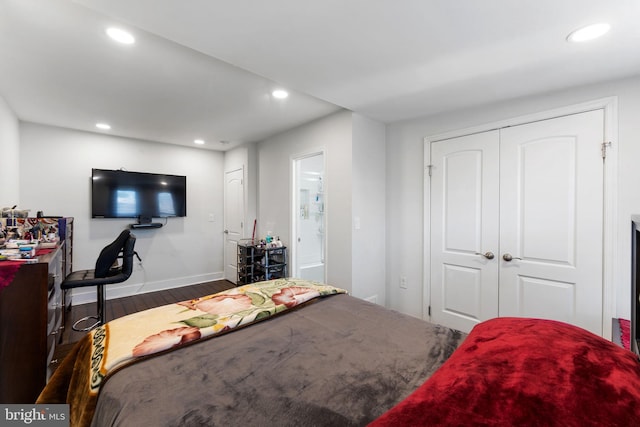 bedroom with recessed lighting, wood finished floors, baseboards, and a closet