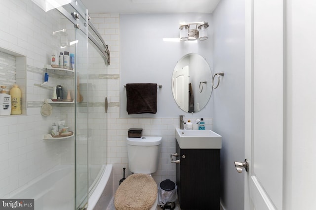 bathroom featuring toilet, vanity, and bath / shower combo with glass door