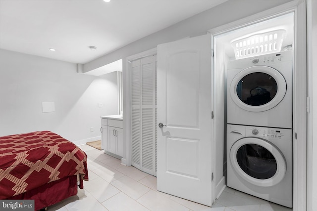 clothes washing area featuring recessed lighting, light tile patterned flooring, baseboards, and stacked washer / drying machine