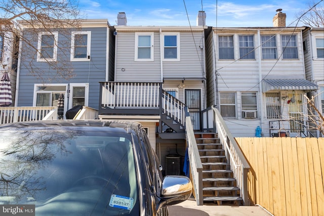 back of property with fence, stairway, cooling unit, a wooden deck, and a chimney