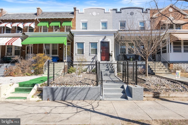 view of front facade with brick siding, a fenced front yard, and a gate