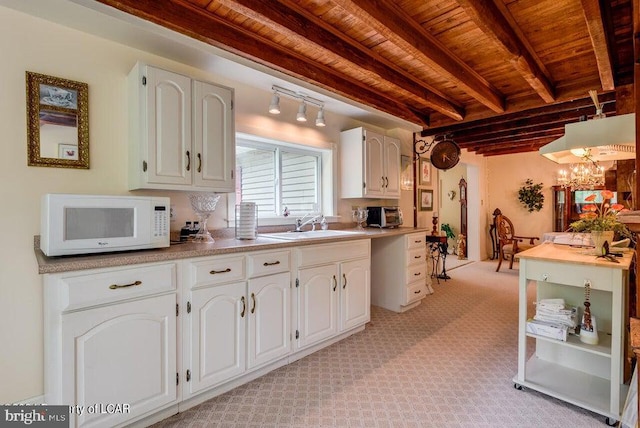 kitchen featuring white microwave, beamed ceiling, white cabinetry, and wood ceiling