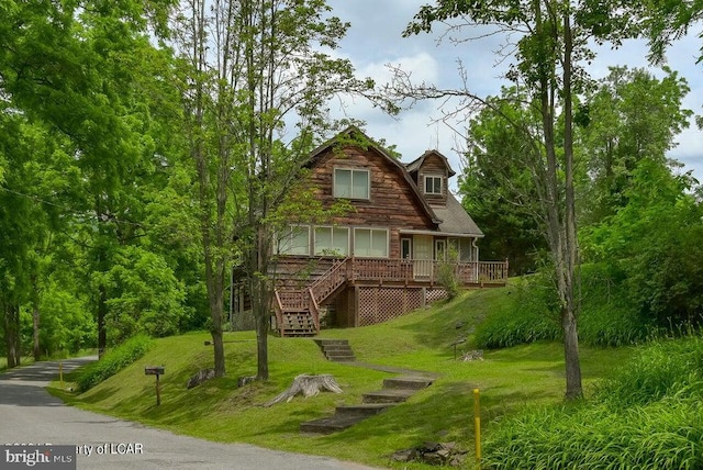 view of front facade with stairs, a wooden deck, and a front yard